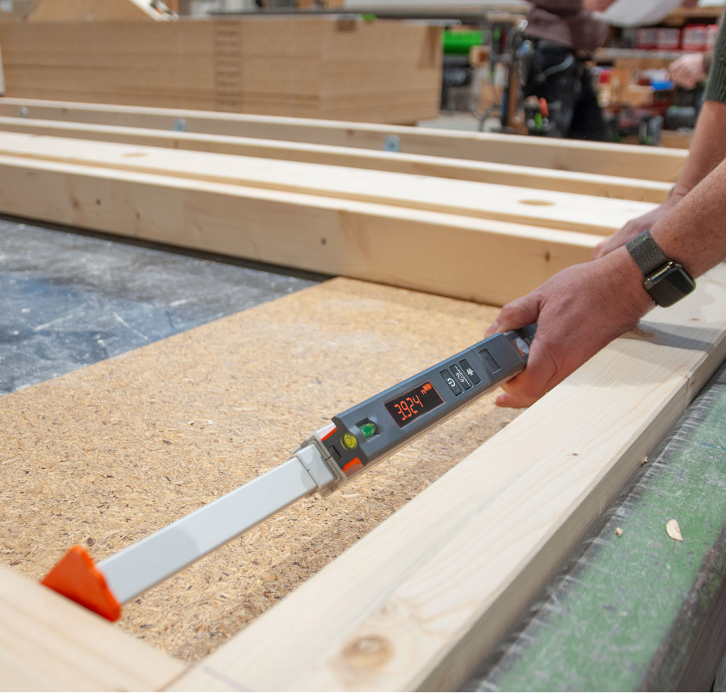 Nedo mEsstronic Digital Measuring Rod 28-118in used by hands to measure a wood plank, digital display shows 3.924.