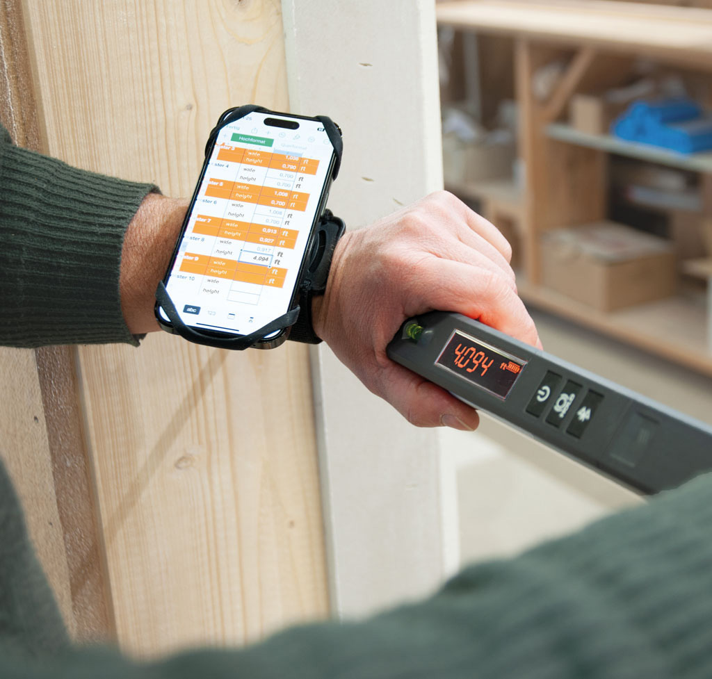 Nedo mEsstronic 2 digital measure held by hand, showing 4.094m on display, smartphone app on wrist